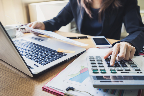 woman planning and filling papers with calculator and a laptop